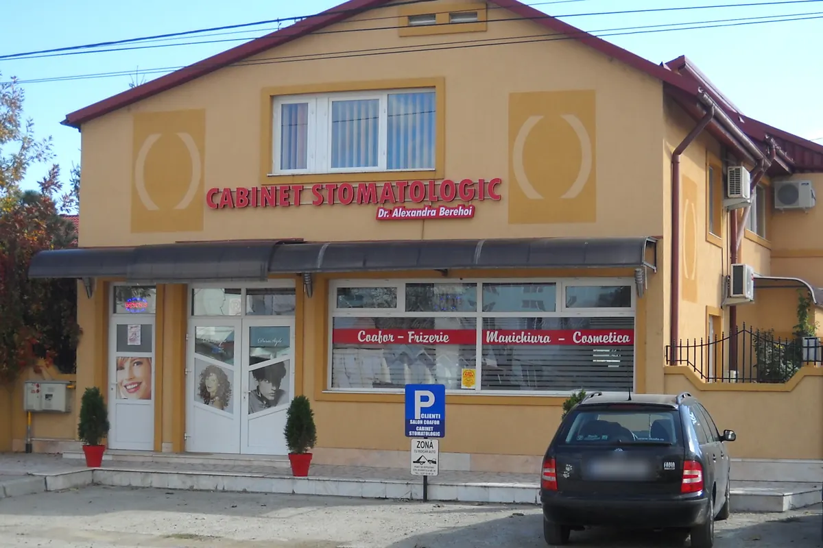 Clădirea galbenă cu acoperiș roșu de pe Aleea Stadionului 7. Pe fațadă, firma roșie „Cabinet stomatologic” și plăcuța „Dr. Alexandra Berehoi”; în față, parcarea.